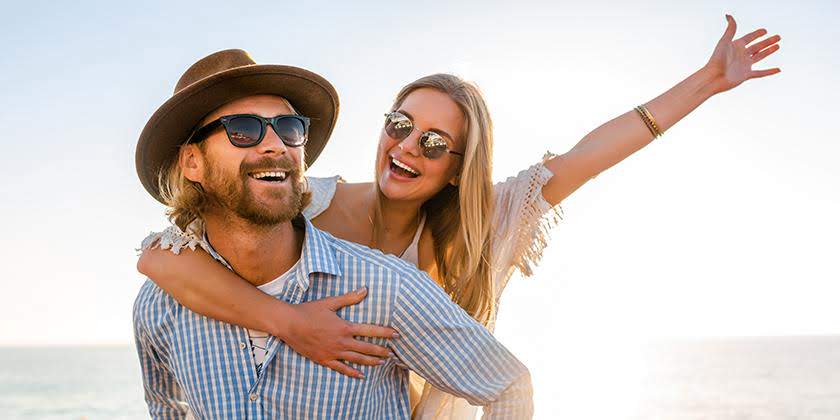 happy couple laughing traveling summer by sea man woman wearing sunglasses